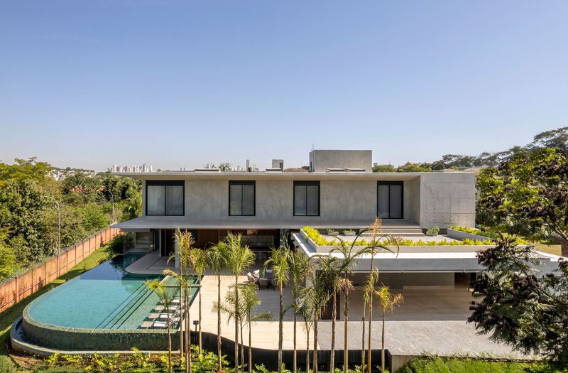 Concrete volume residence with cantilevered roof plane above curved pool and young palm plantings
