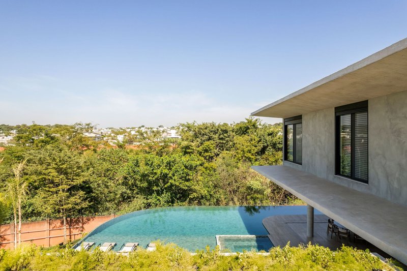 Cantilevered concrete terrace overlooking infinity-edge pool and forested hillside in afternoon light