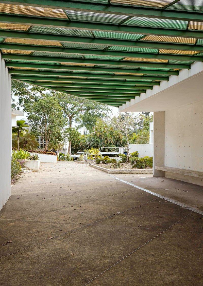 View through covered passage toward landscaped courtyard with planted beds and mature trees