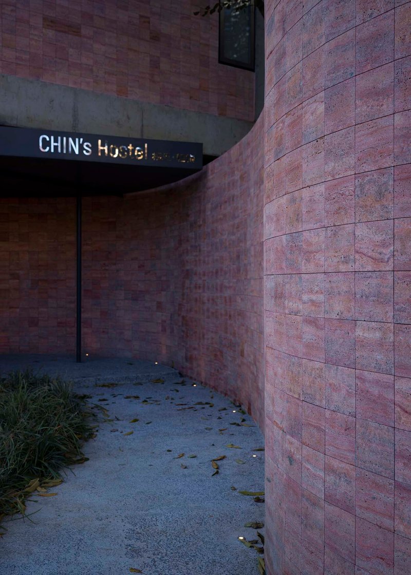 Curved entrance passage with red sandstone walls and scattered leaves on the pavement at dusk