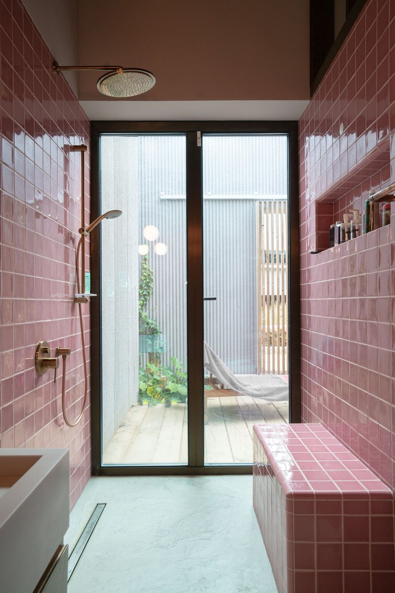 Bathroom clad in pink subway tiles with glazed doors opening to an enclosed timber deck