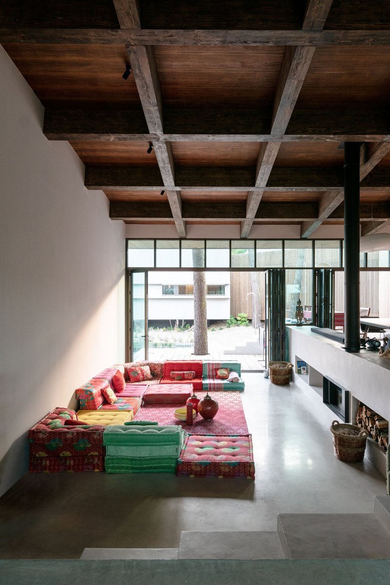 Living area with exposed timber beam ceiling and polished concrete floor overlooking planted courtyard