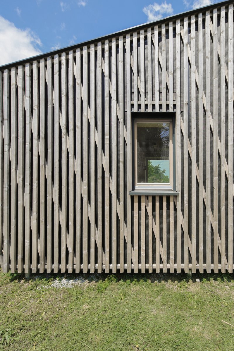 Weathered vertical timber slat facade with a single window under a clear sky