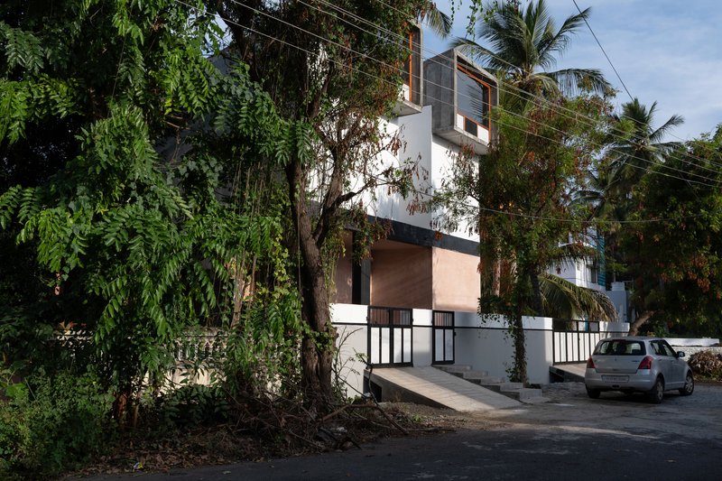 Street view of the white facade with concrete window boxes and palm trees overhead