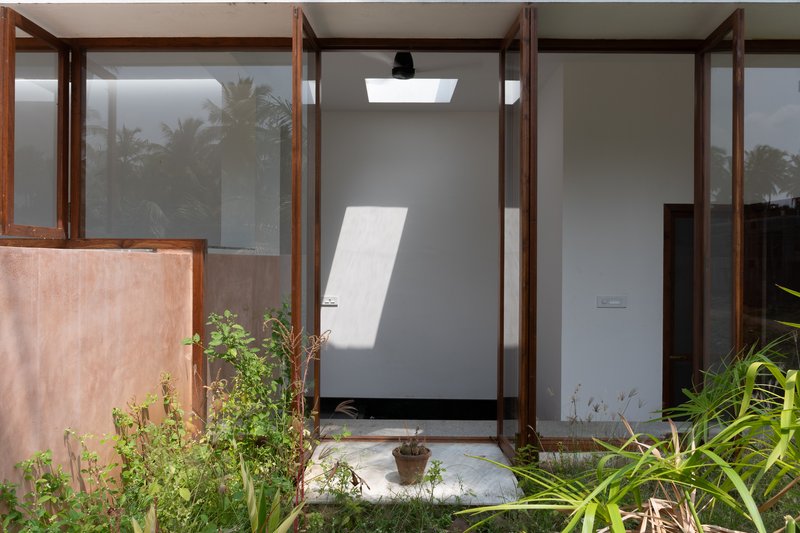 Glazed entry door with timber frame and skylight casting angular shadows on white wall