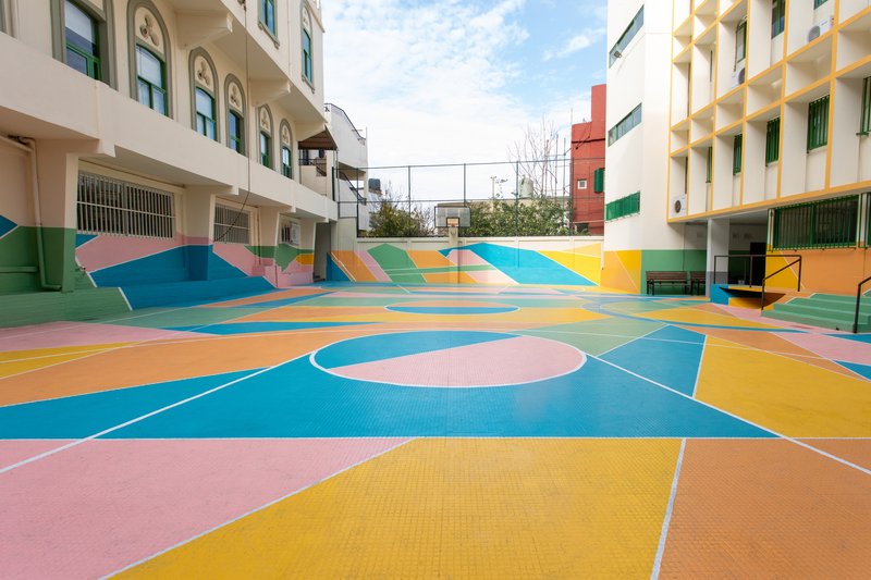 Basketball court painted with abstract geometric patterns in pink, blue, yellow, and orange