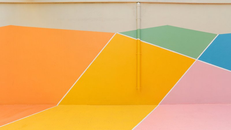 Close-up of diagonal color bands meeting at a vertical drainage pipe on the court surface