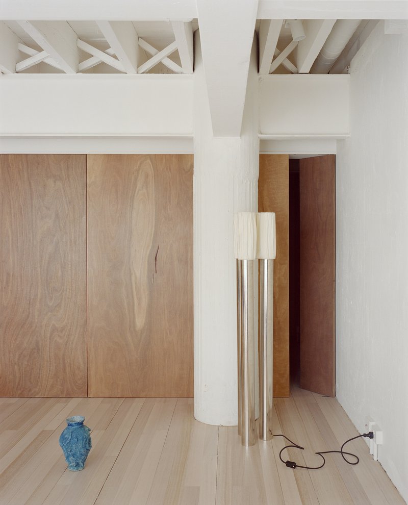 Room corner showing exposed timber ceiling structure, oak paneling, white column and blue ceramic vase
