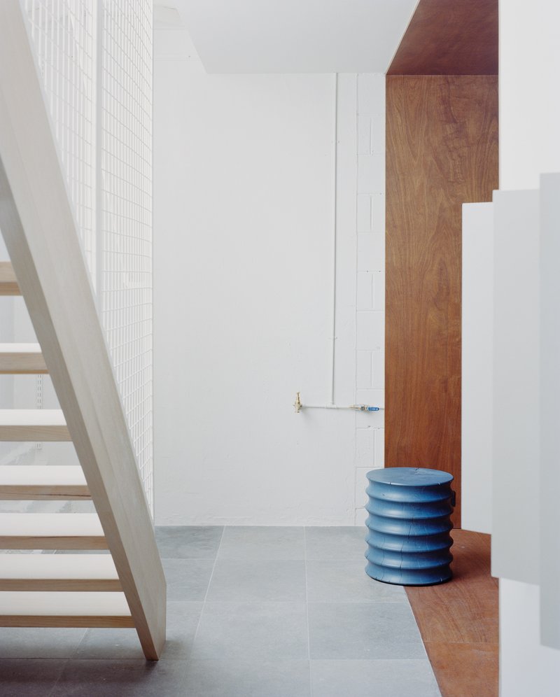 Stairwell view with timber treads, white mesh screen wall, oak paneling and blue stacked seat