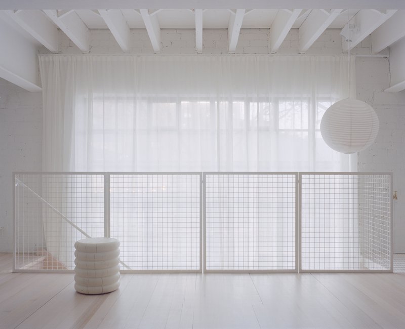 Interior mezzanine with wire mesh balustrade and white timber ceiling beams in diffused daylight
