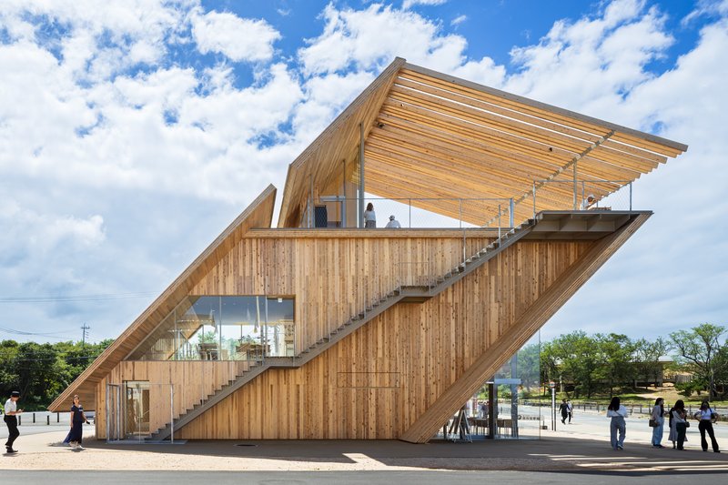 Side elevation showing the vertical timber cladding and diagonal staircase against scattered clouds