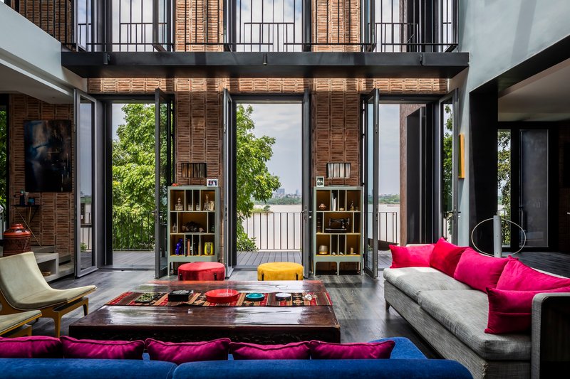 Open doors revealing outdoor terrace with water views beyond the double-height living space