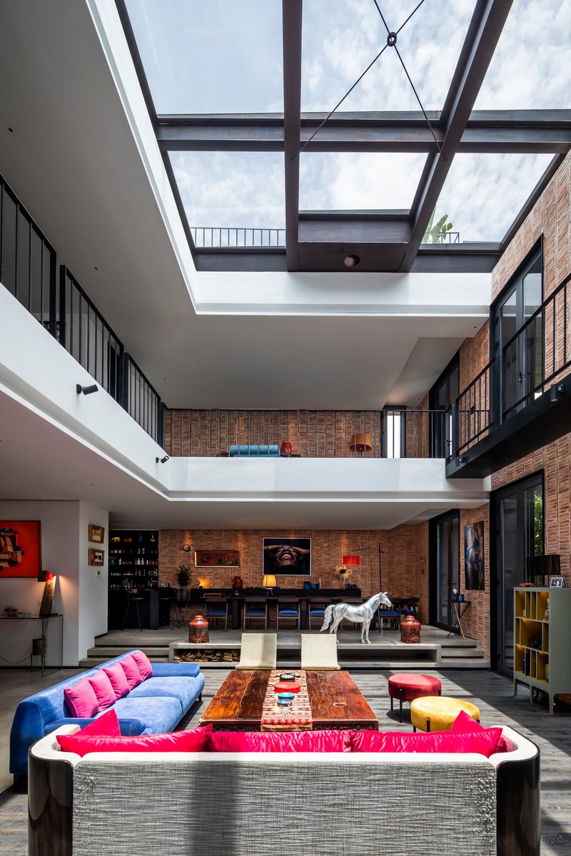 Double-height living space with exposed brick walls and a glazed steel skylight overhead