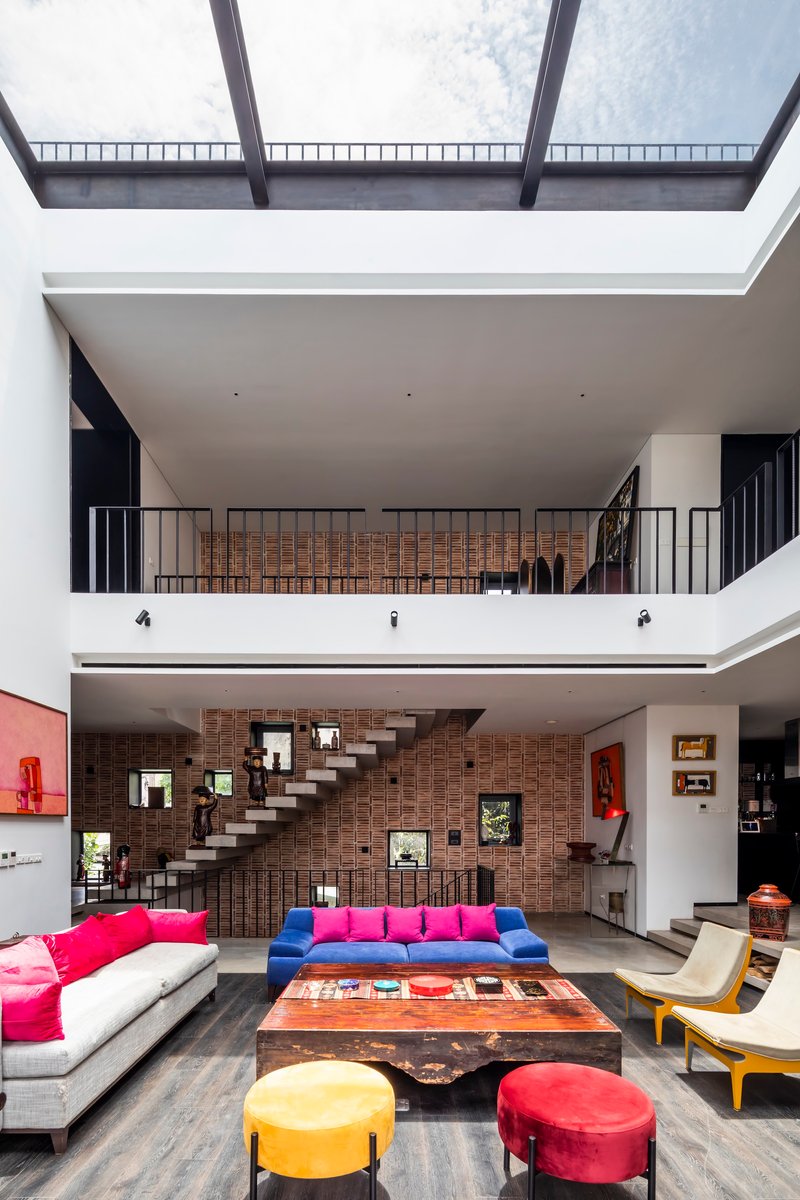 Central void framed by white balconies and a continuous skylight bringing diffused daylight down