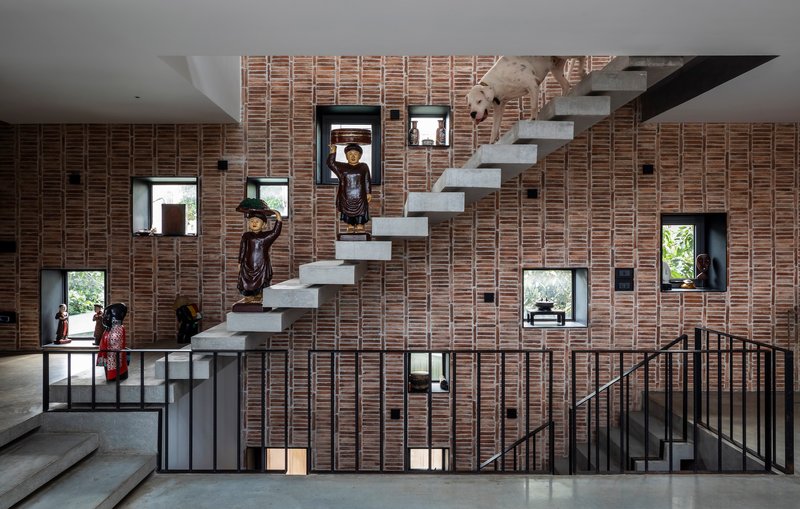 Cantilevered concrete stair treads against a perforated brick wall with residents in view