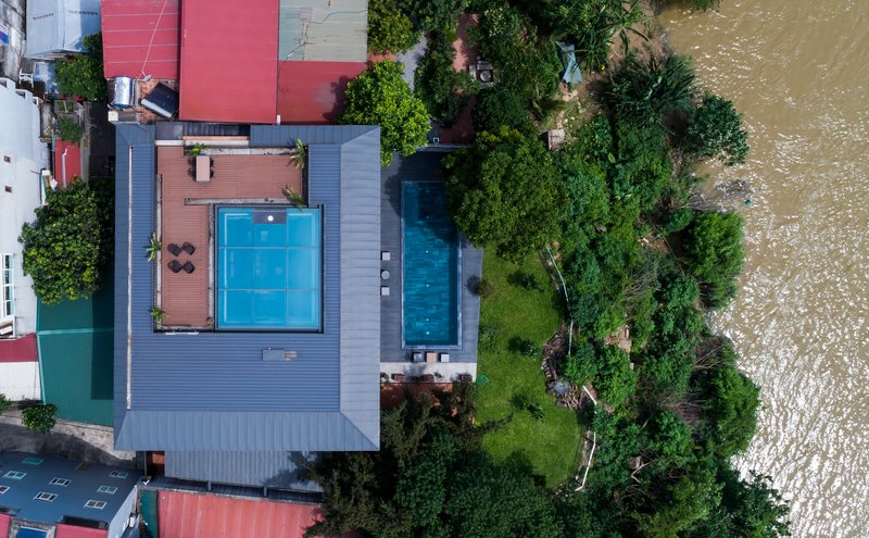 Aerial view of the cantilevered volume with swimming pool and terrace adjacent to a riverbank