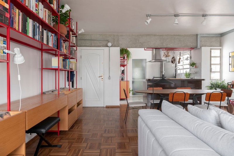 Open-plan living space showing red shelving, white barn door and exposed concrete ceiling beam