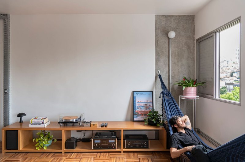 Corner with person reclining in hammock beside window and low storage unit