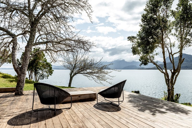 Timber deck with lounge chairs overlooking the lake and distant mountains under partly cloudy skies
