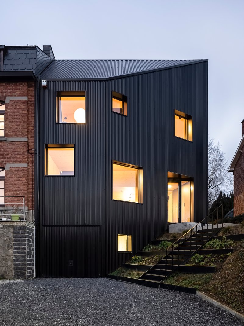 The facade with illuminated interior spaces visible through scattered window openings at dusk
