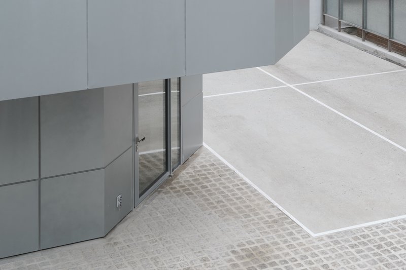 Looking down at the curved entry door with cobblestone and concrete paving meeting at the threshold