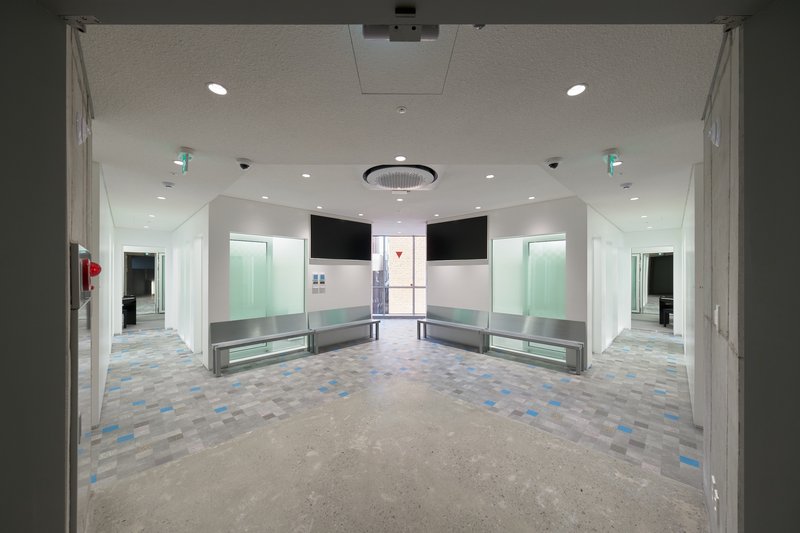 Interior lobby with patterned terrazzo floor, built-in benches and glazed openings at both ends
