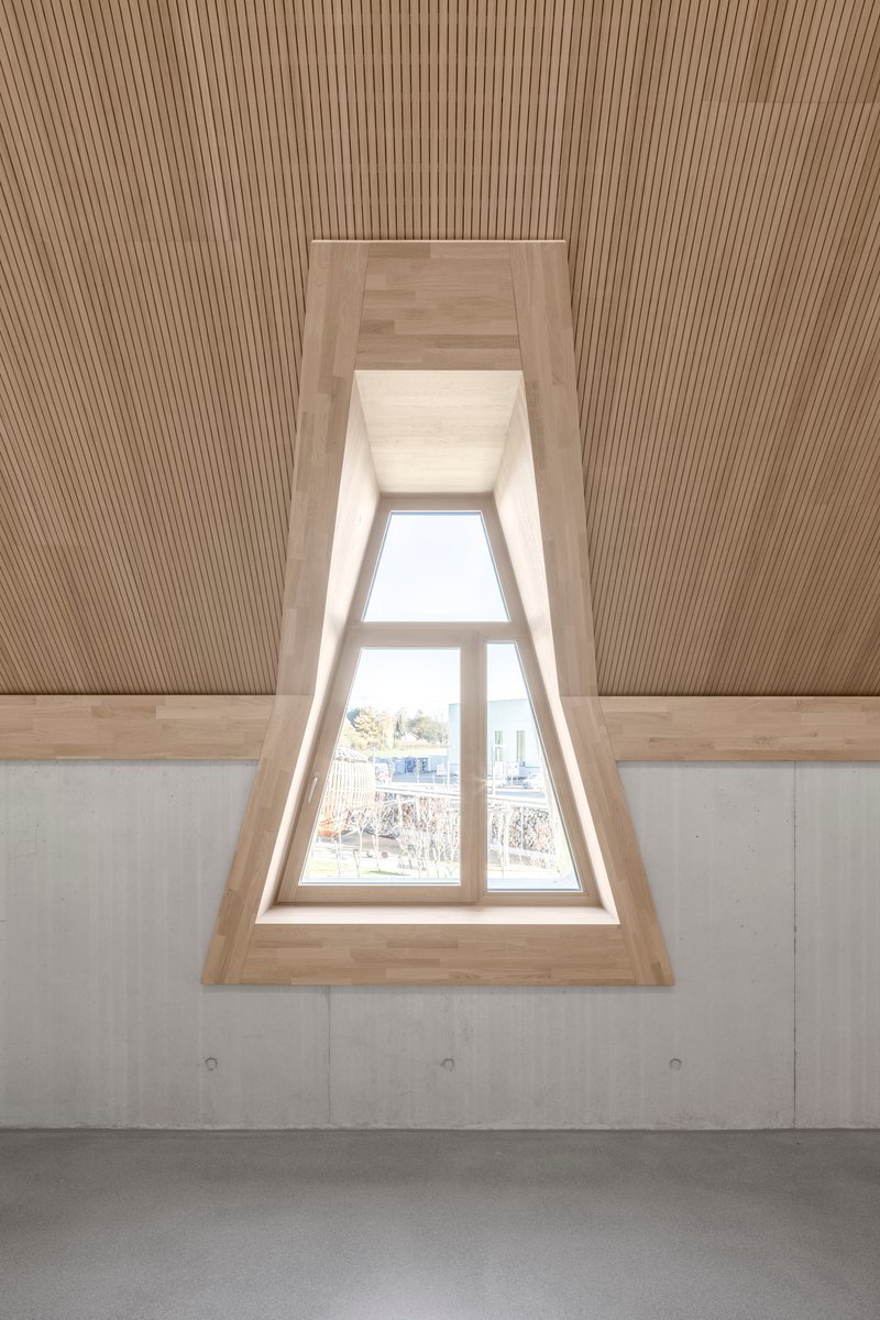 Recessed triangular dormer window with timber lining and ribbed ceiling above bare concrete walls