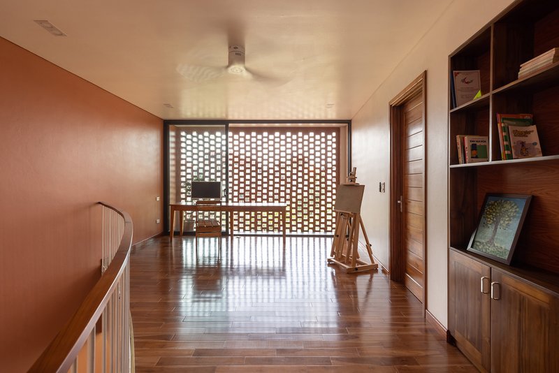 Upper hallway with timber flooring leading to a perforated brick screen and rocking chair