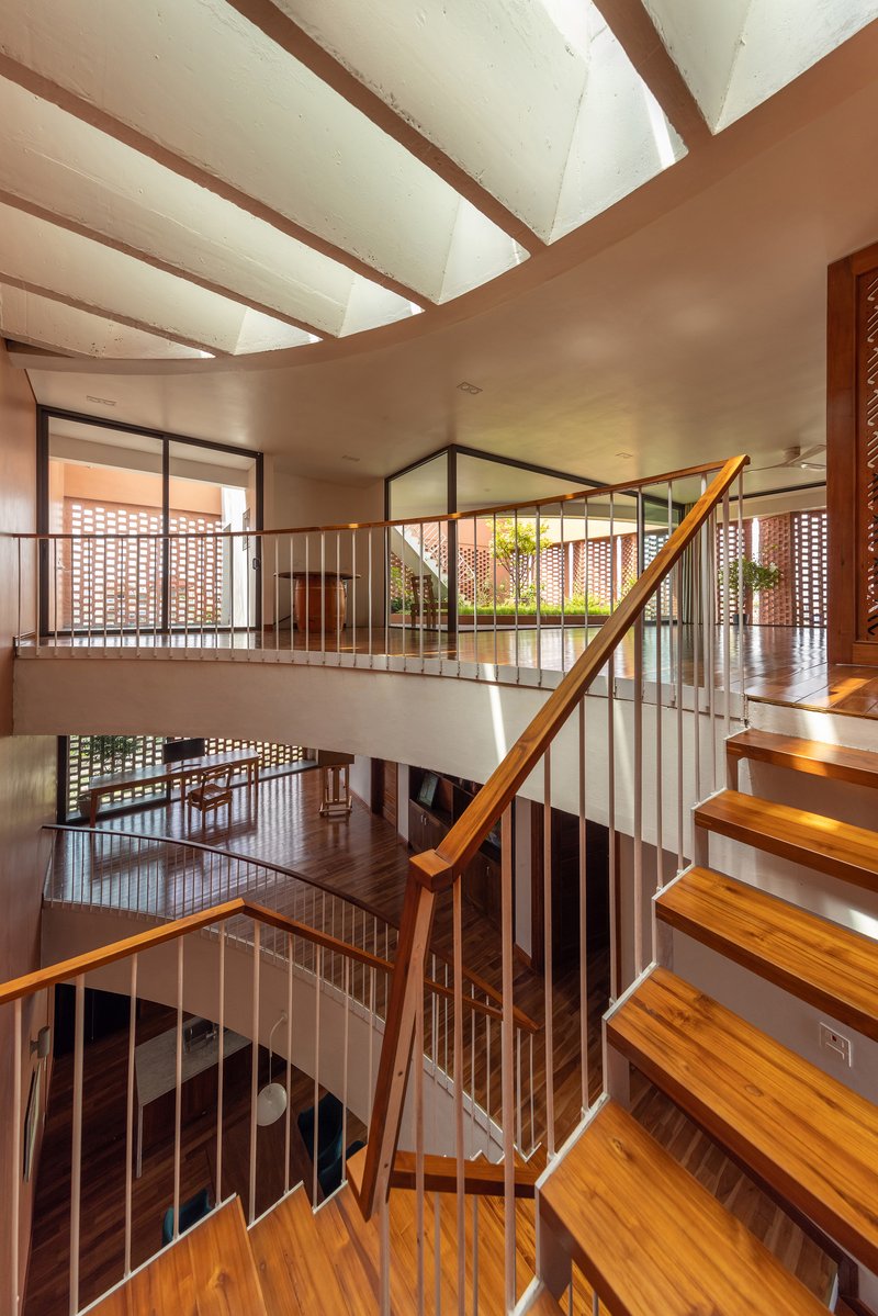 Multi-level staircase with timber treads and metal railings wrapping around an open courtyard void