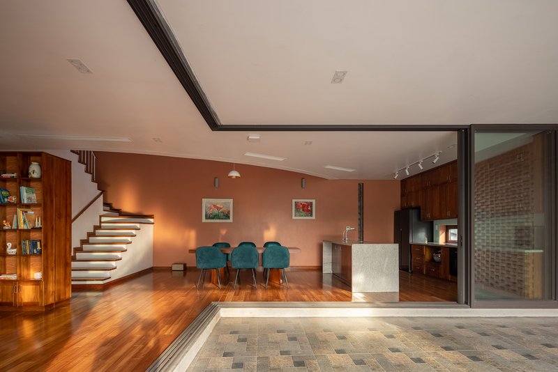 Living space opening to paved courtyard through sliding glass doors beside a curved staircase