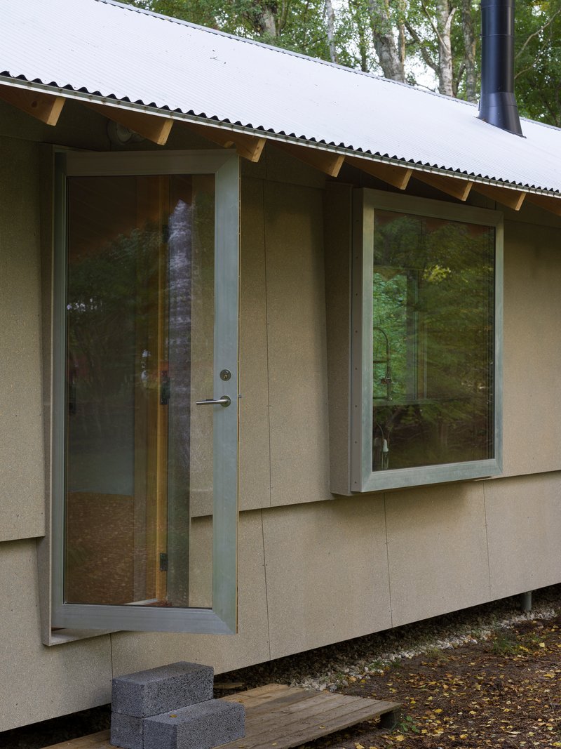 Close-up of the entrance door and window corner with exposed timber rafter brackets overhead