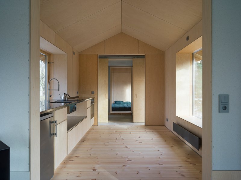 Interior view through the kitchen showing plywood-lined vaulted ceiling and doorway to bedroom beyond