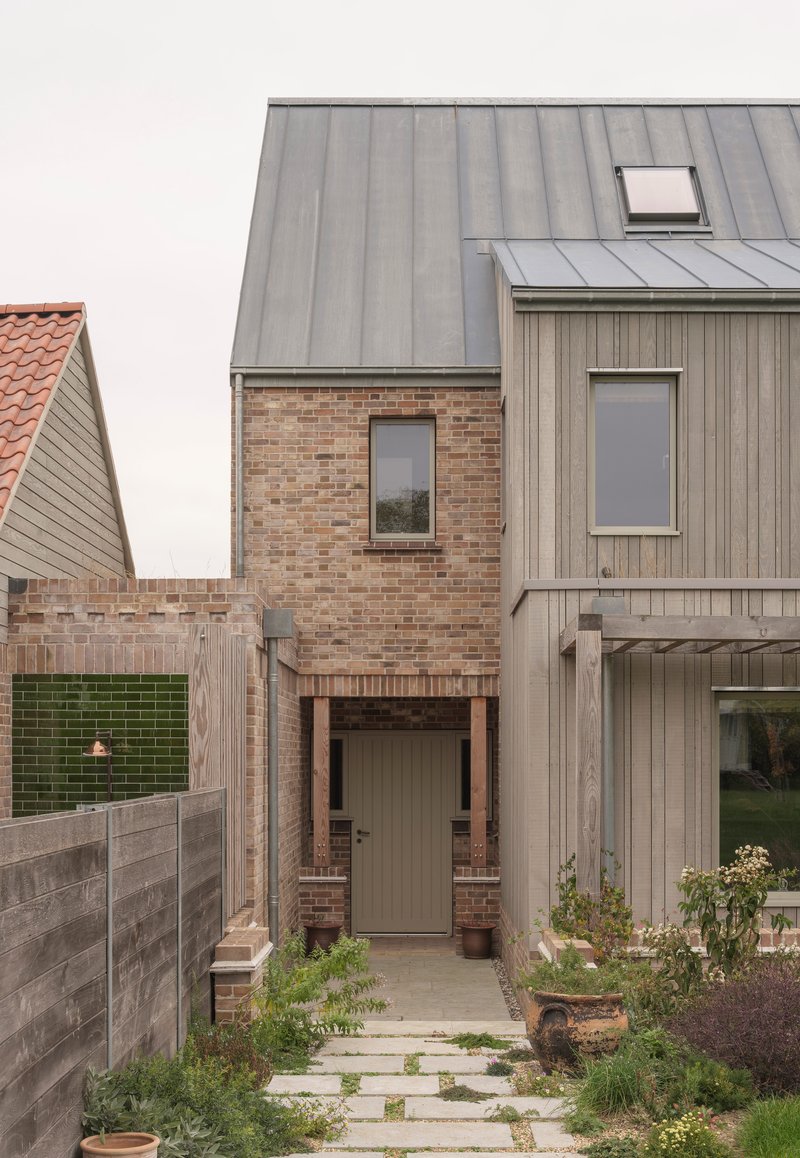 Side entry path with paving stones between brick walls and weathered timber cladding