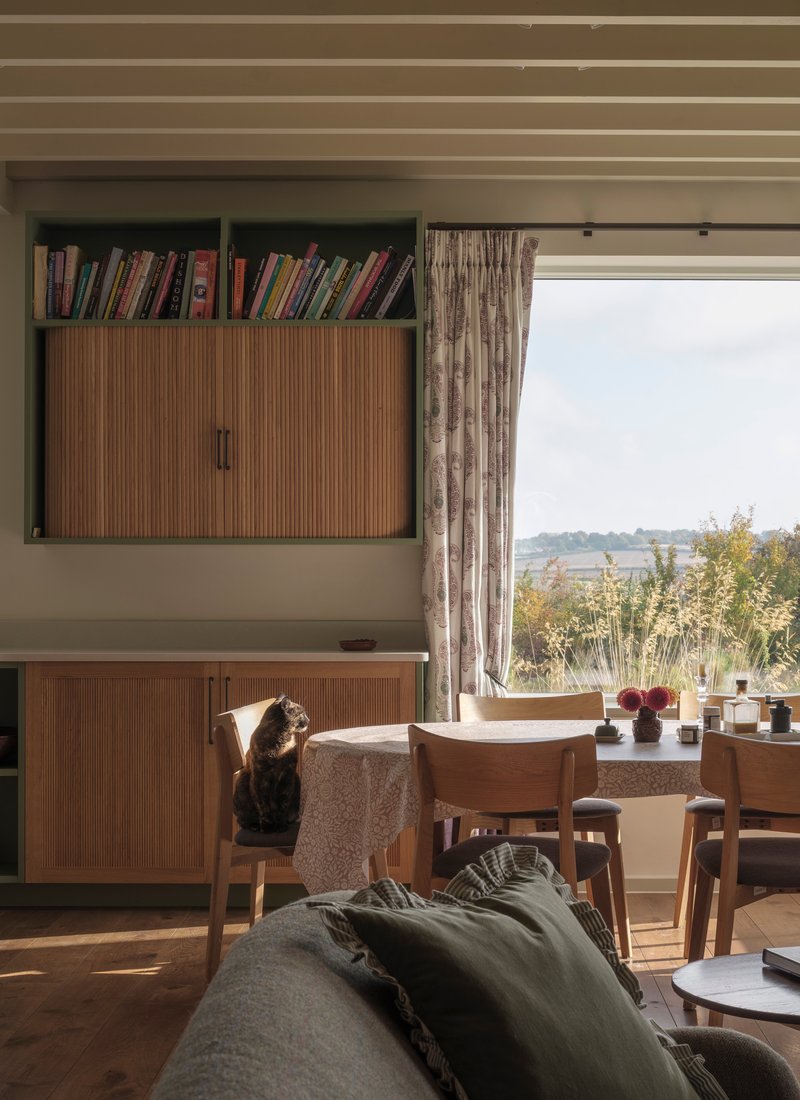 Living area with built-in storage, a cat on the bench and countryside views through the window