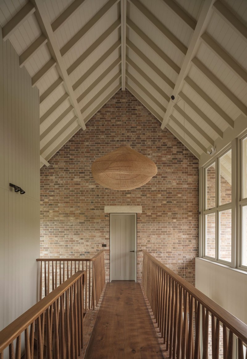 Upper landing with vaulted timber ceiling and brick gable wall flanked by wooden balustrades