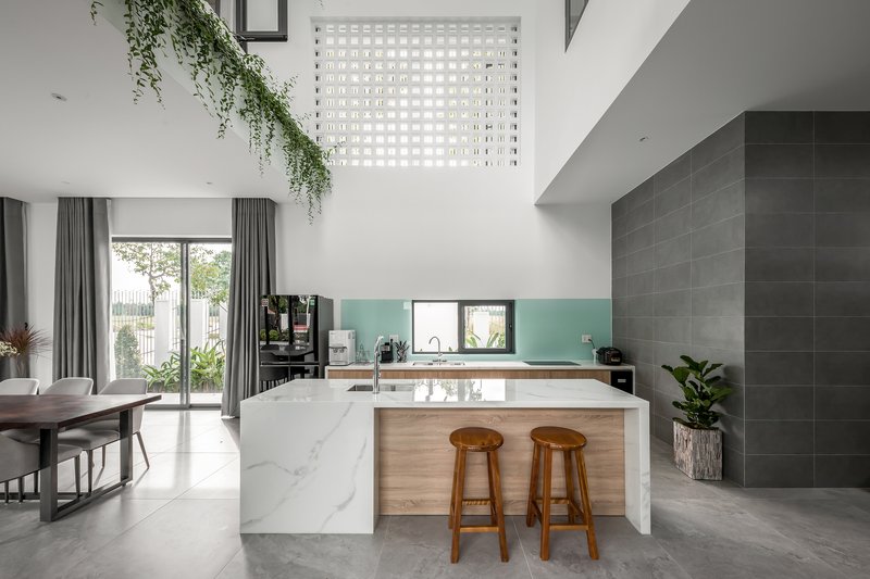 Open kitchen and dining area with marble island and perforated screen bringing daylight from above