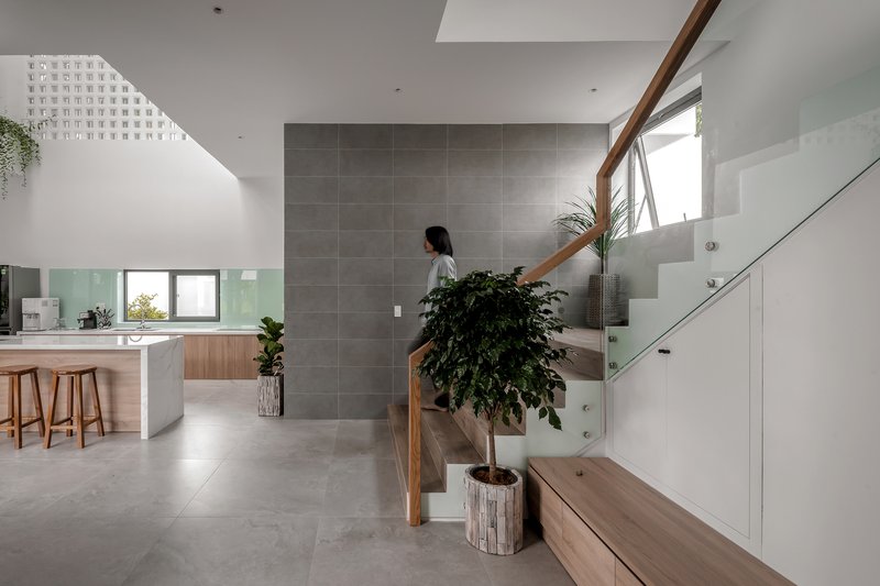 Grey tiled feature wall anchoring an open stairwell lit by a perforated skylight above