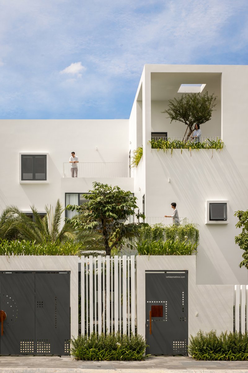 Street facade showing white volumes with recessed balconies and residents on upper terraces