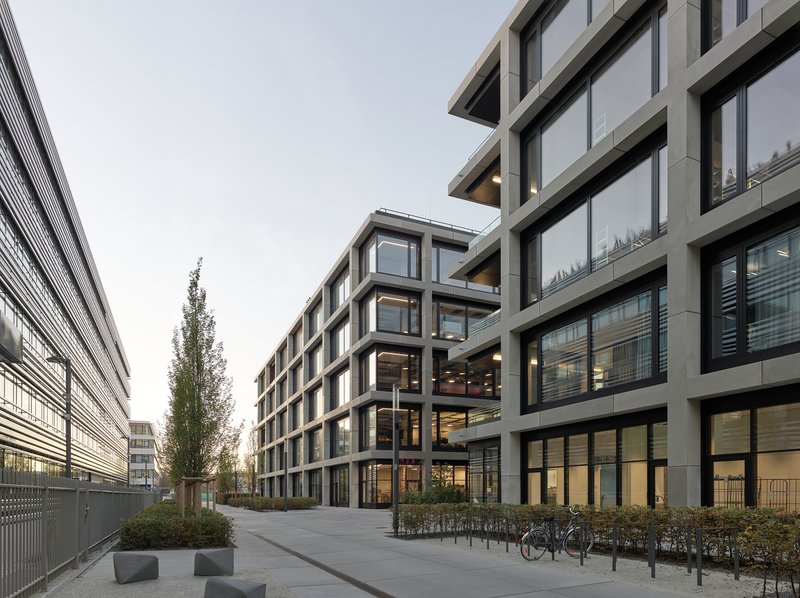 Courtyard view at dusk showing the gridded facade with interior lights glowing and bicycles parked below