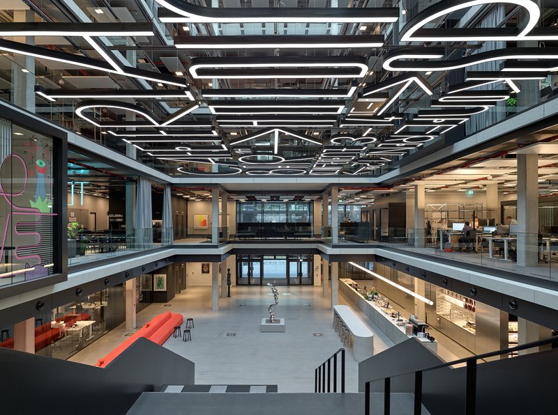 Multi-story atrium with graphic white light fixtures suspended above open office floors and a central void