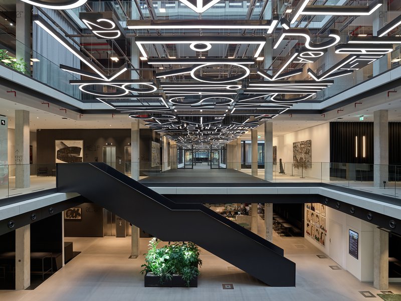 Atrium view showing the black steel bridge, custom linear pendant lights and gallery spaces on lower floors