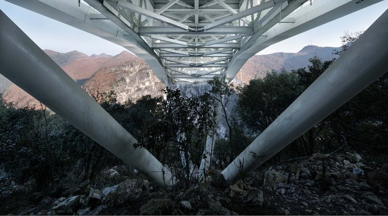 Underside view of the steel support columns and triangulated truss framework at dusk