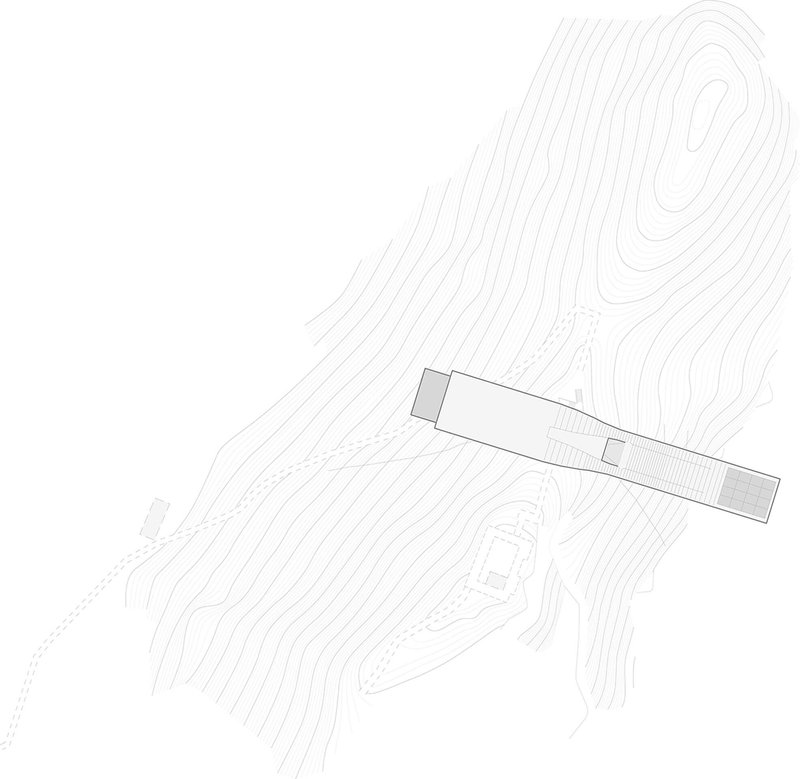 Site plan drawing showing a linear building positioned across contoured terrain with a rocky outcrop