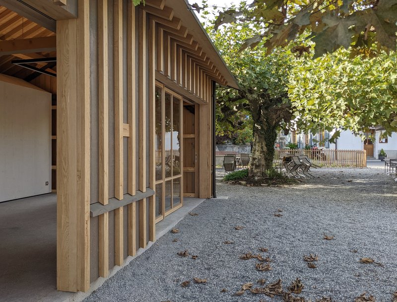 Glazed entrance set within vertical timber slat facade with overhanging eaves and adjacent trees