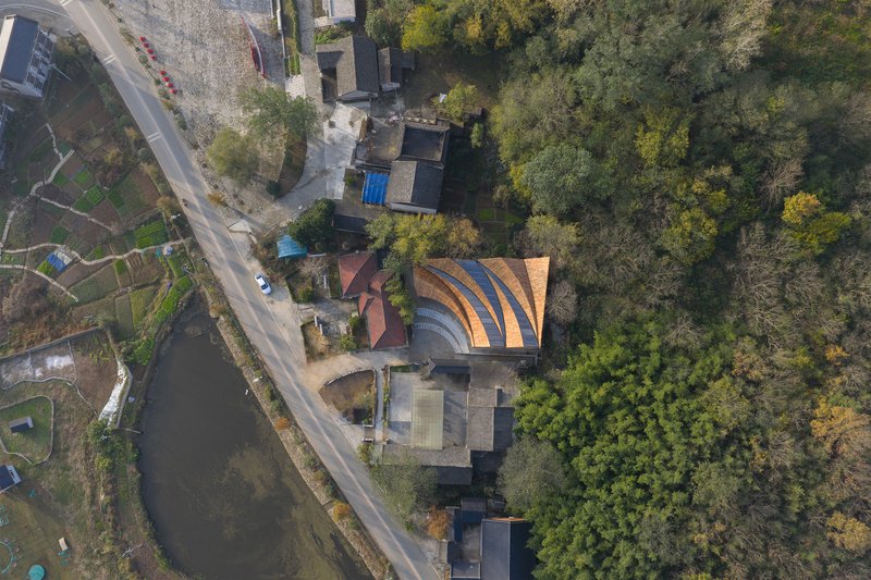 Overhead view showing the undulating timber roof forms adjacent to a canal and residential gardens