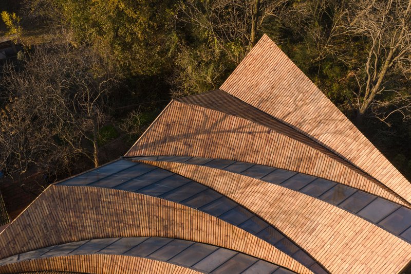 Aerial view of overlapping triangular roof planes clad in ribbed tile and dark metal flashing