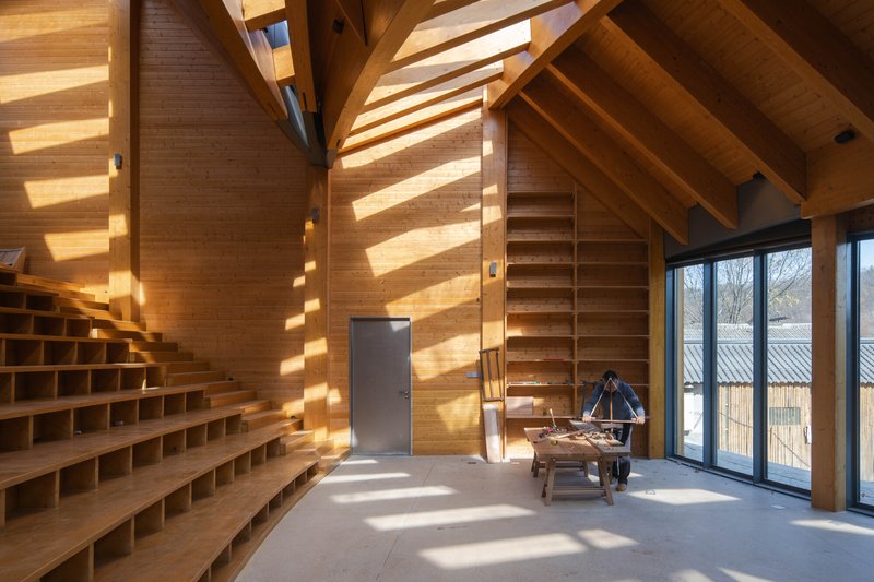 Timber-lined reading room with built-in shelving and horizontal bands of sunlight striping the wall