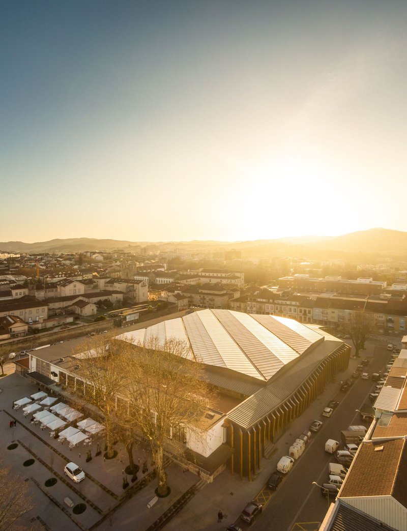 Elevated view of the metal roof and timber colonnade at sunset with mountains beyond
