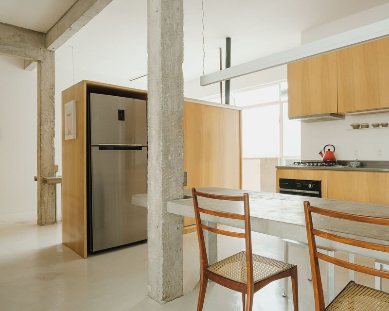 Kitchen with light wood cabinetry and concrete counter wrapping around a structural column