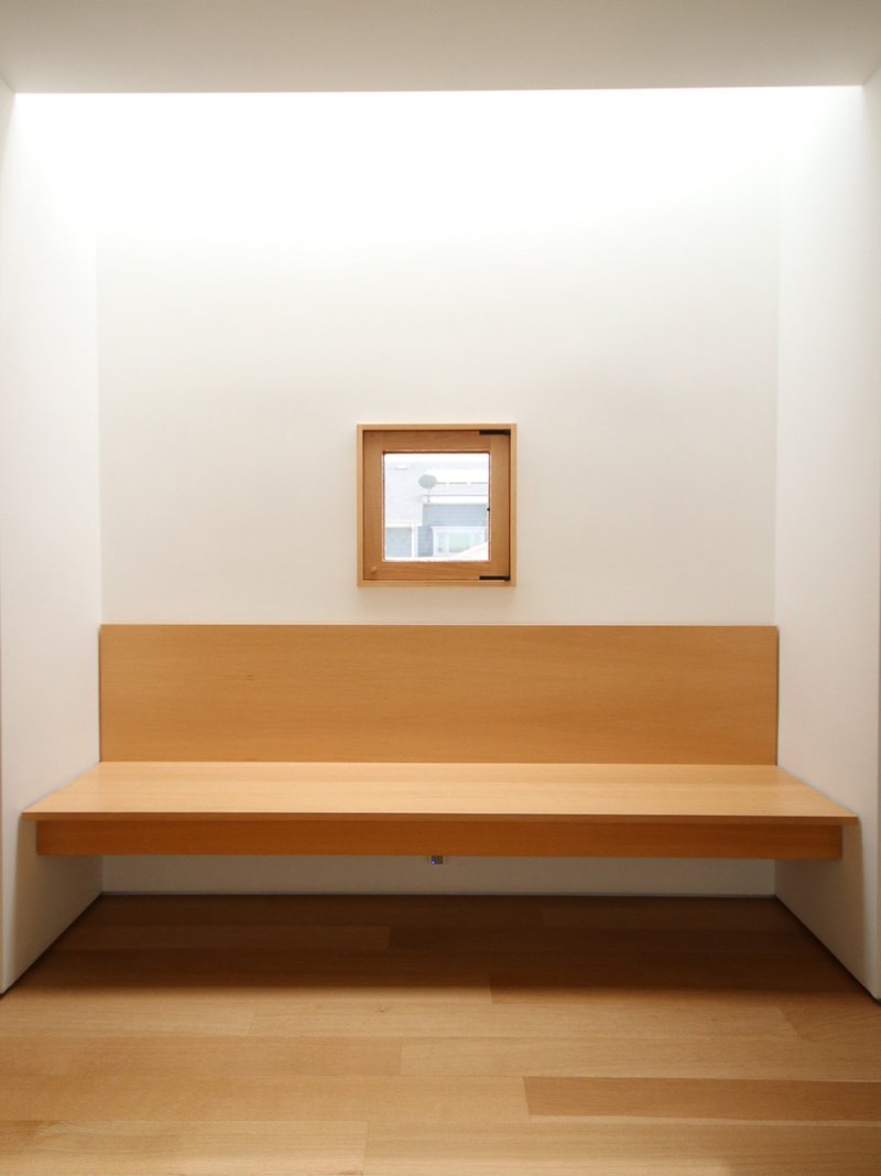 Built-in timber bench set into white alcove beneath a framed window